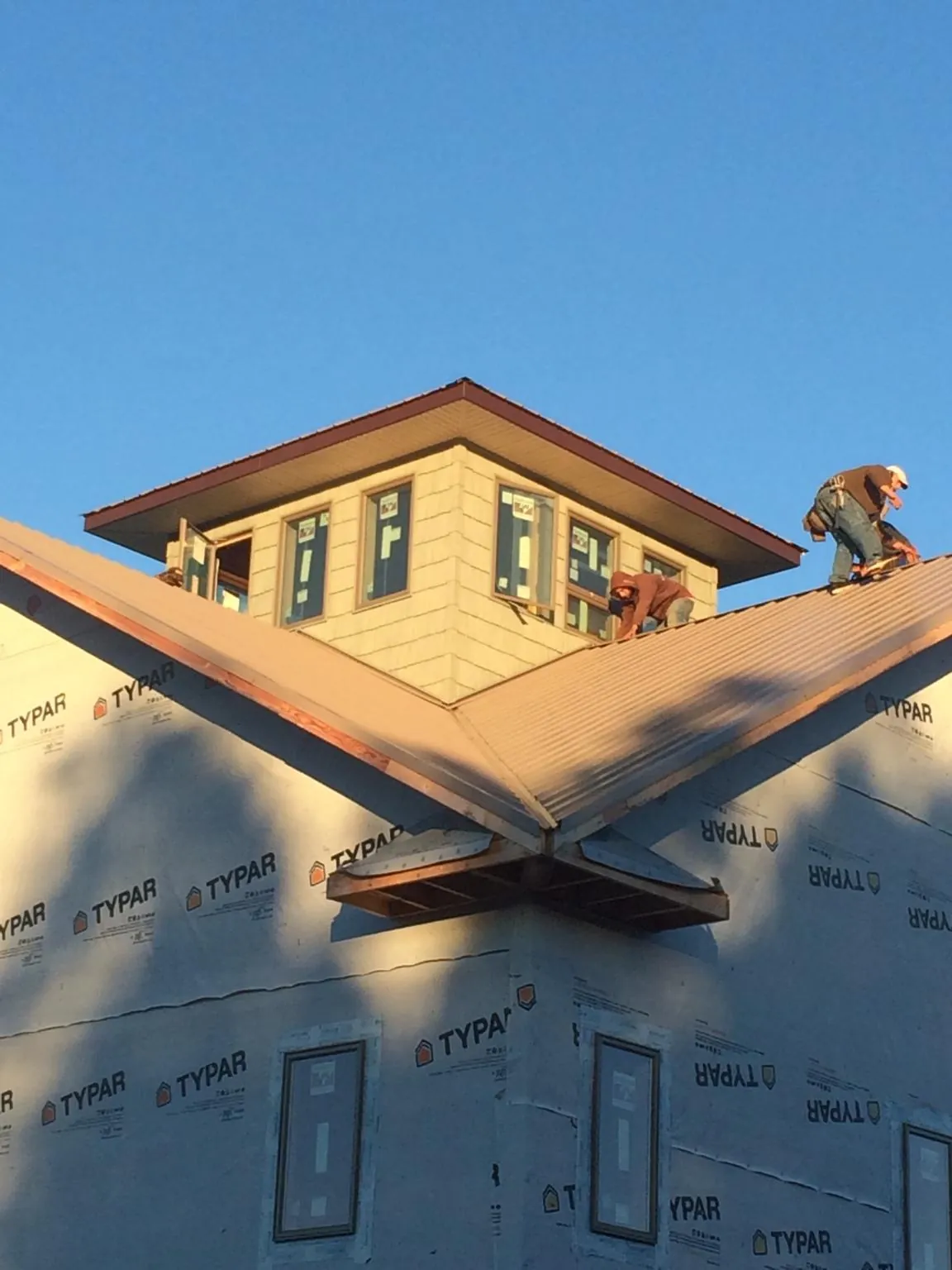 Roofers working around a rooftop cupola on a new metal roof at sunset — Roof Waterproofing in Ellsworth by Roofing Brothers